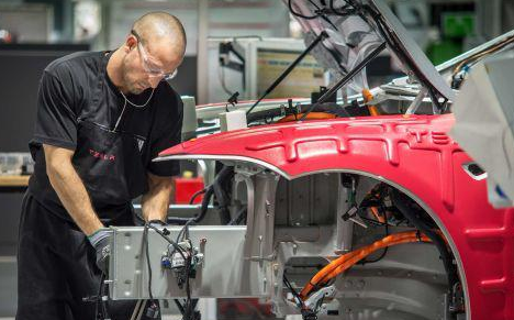 工人們?cè)谔厮估挥诩又莞ダ锩商氐墓S里組裝汽車